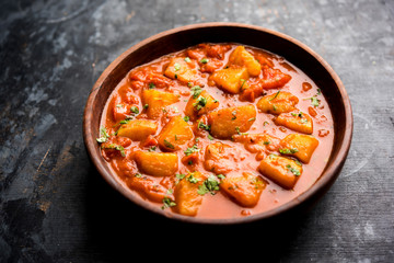 Indian food - Aloo curry masala. Potato cooked with spices and herbs in a tomato curry. served in a bowl over moody background. selective focus