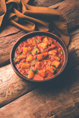 Indian food - Aloo curry masala. Potato cooked with spices and herbs in a tomato curry. served in a bowl over moody background. selective focus