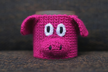 Knitted hot mug warmer in a shape of a funny pink pig. New Year 2019 theme