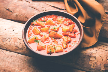 Indian food - Aloo curry masala. Potato cooked with spices and herbs in a tomato curry. served in a bowl over moody background. selective focus
