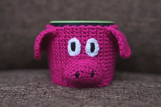 Knitted hot mug warmer in a shape of a funny pink pig. New Year 2019 theme