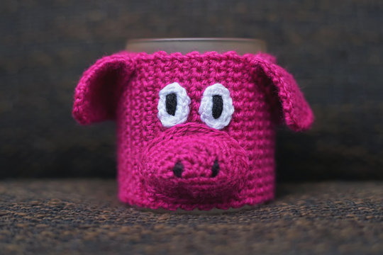 Knitted hot mug warmer in a shape of a funny pink pig. New Year 2019 theme