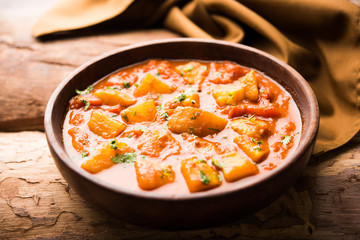 Indian food - Aloo curry masala. Potato cooked with spices and herbs in a tomato curry. served in a bowl over moody background. selective focus