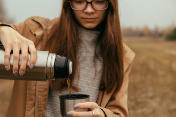 A young girl holds a thermos in her hands. Travel and tourism concept