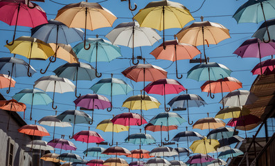 Fototapeta na wymiar Low angle of colorful umbrellas hanging in rows and decorating street on sunny day in summer in Antalya