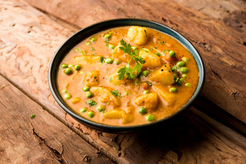 Indian Aloo Mutter curry - Potato and Peas immersed in an Onion Tomato Gravy and garnished with coriander leaves. Served in a Karahi/kadhai or pan or bowl. selective focus