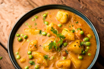 Indian Aloo Mutter curry - Potato and Peas immersed in an Onion Tomato Gravy and garnished with coriander leaves. Served in a Karahi/kadhai or pan or bowl. selective focus