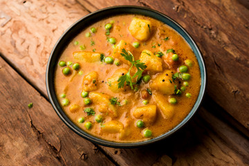 Indian Aloo Mutter curry - Potato and Peas immersed in an Onion Tomato Gravy and garnished with coriander leaves. Served in a Karahi/kadhai or pan or bowl. selective focus
