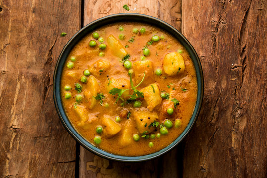 Indian Aloo Mutter curry - Potato and Peas immersed in an Onion Tomato Gravy and garnished with coriander leaves. Served in a Karahi/kadhai or pan or bowl. selective focus