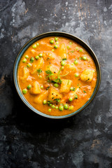 Indian Aloo Mutter curry - Potato and Peas immersed in an Onion Tomato Gravy and garnished with coriander leaves. Served in a Karahi/kadhai or pan or bowl. selective focus