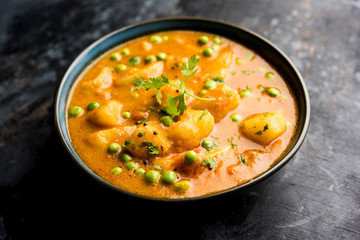 Indian Aloo Mutter curry - Potato and Peas immersed in an Onion Tomato Gravy and garnished with coriander leaves. Served in a Karahi/kadhai or pan or bowl. selective focus