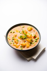 Indian Aloo Mutter curry - Potato and Peas immersed in an Onion Tomato Gravy and garnished with coriander leaves. Served in a Karahi/kadhai or pan or bowl. selective focus