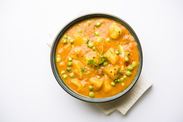 Indian Aloo Mutter curry - Potato and Peas immersed in an Onion Tomato Gravy and garnished with coriander leaves. Served in a Karahi/kadhai or pan or bowl. selective focus