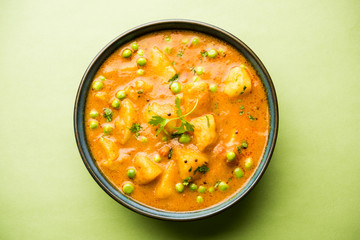 Indian Aloo Mutter curry - Potato and Peas immersed in an Onion Tomato Gravy and garnished with coriander leaves. Served in a Karahi/kadhai or pan or bowl. selective focus