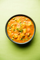 Indian Aloo Mutter curry - Potato and Peas immersed in an Onion Tomato Gravy and garnished with coriander leaves. Served in a Karahi/kadhai or pan or bowl. selective focus