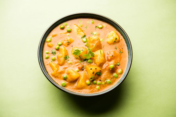 Indian Aloo Mutter curry - Potato and Peas immersed in an Onion Tomato Gravy and garnished with coriander leaves. Served in a Karahi/kadhai or pan or bowl. selective focus