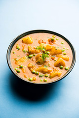 Indian Aloo Mutter curry - Potato and Peas immersed in an Onion Tomato Gravy and garnished with coriander leaves. Served in a Karahi/kadhai or pan or bowl. selective focus