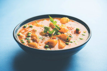 Indian Aloo Mutter curry - Potato and Peas immersed in an Onion Tomato Gravy and garnished with coriander leaves. Served in a Karahi/kadhai or pan or bowl. selective focus