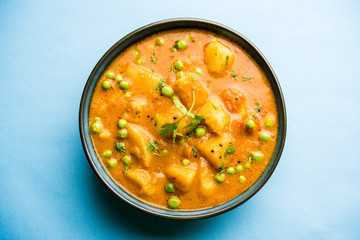 Indian Aloo Mutter curry - Potato and Peas immersed in an Onion Tomato Gravy and garnished with coriander leaves. Served in a Karahi/kadhai or pan or bowl. selective focus