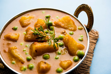 Indian Aloo Mutter curry - Potato and Peas immersed in an Onion Tomato Gravy and garnished with coriander leaves. Served in a Karahi/kadhai or pan or bowl. selective focus