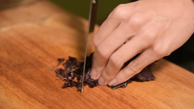 Closeup of the hands of a girl at the home kitchen on a wooden cutting board small cherry tomatoes. Home cooking