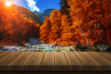 Naklejka na ściany i meble Empty wooden table for product placement or montage with focus to table top in the foreground. Mock up for display of product. Beautiful background with forest, waterfall, incredible landscape.