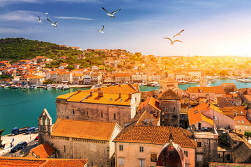 Fototapeta premium View at town Trogir, old touristic place in Croatia Europe with seagull's flying over city. Trogir town coastal view. Magnificent Trogir, Croatia. Sunny old Venetian town, Dalmatian Coast in Croatia.