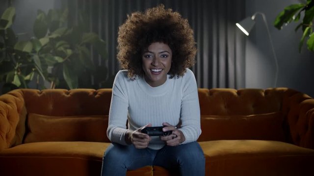 Female gamer playing video games at home.