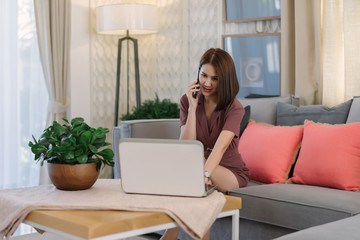 Beautiful Asian businesswoman discuss mobile phone calls with customers and work on laptops at home or modern offices.