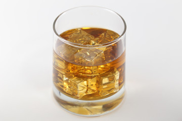 Glass of Whiskey and Ice Cubes Set Against a White Background