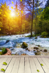 Empty wooden table for product placement or montage with focus to table top in the foreground. Mock up for display of product. Beautiful background with forest, waterfall, incredible landscape.