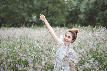 Naklejka na ściany i meble Woman with the white dress in the middle of the meadow with violet flowers Murdannia Giganteum in Prachinburi, Thailand. Photographer in nature. 
