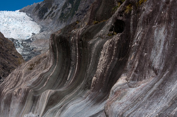 Strange rock formations in the foreground and the Franz Josef Glacier in the background in the Mt....