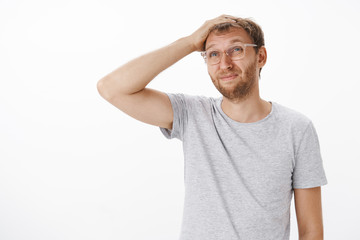 Waist-up shot of silly confused adult father with bristle in glasses scratching top of head...