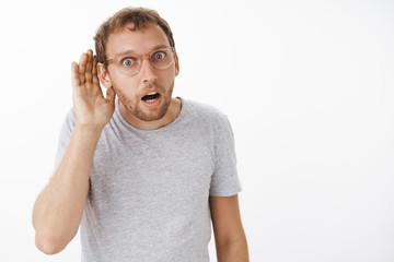 You say what. Intense focused intrigued man with bristle in glasses bending towards with hand near...