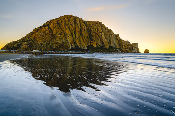 Moro Rock in Morro Bay, California, beautiful reflection in the water, blue waves and colorful sky