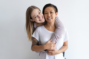 Cheerful women embracing and looking at camera. Diverse homosexual couple. Lesbian couple concept. Isolated front view on white background.