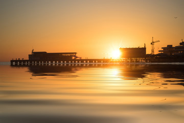 sunset over the pier and sea with big waves