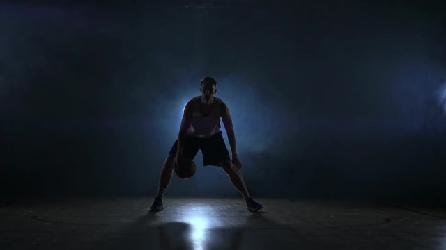 A solo basketball player does some dribbling moves in front of the camera