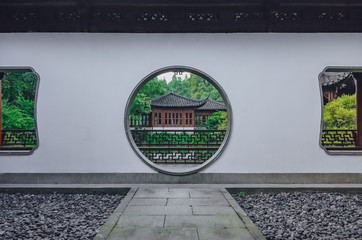 Path leading to moon gate with view of traditional Chinese building, in a Chinese garden, near West Lake, in Hangzhou, China