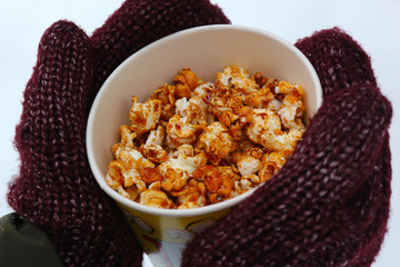 Young woman holding popcorn in winter, in mittens