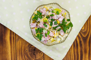 Tasty salad with sausage, green pea, canned corn, bell pepper, cucumber and mayonnaise on wooden table. Top view