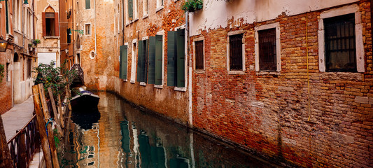 Building is flooded with water. Brick house green shutters on Windows river channel. Venice