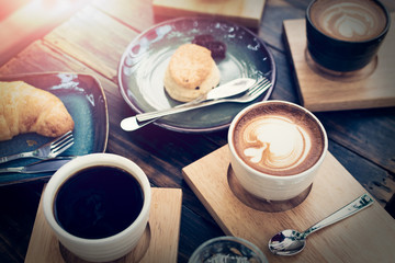 Breakfast with coffee and bread on wooden table.