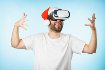 Naklejka premium Man in virtual reality goggles and santa hat