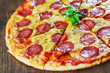 Pepperoni Pizza with Mozzarella cheese, salami, Tomato sauce, pepper, Spices and Fresh Basil. Italian pizza on wooden background