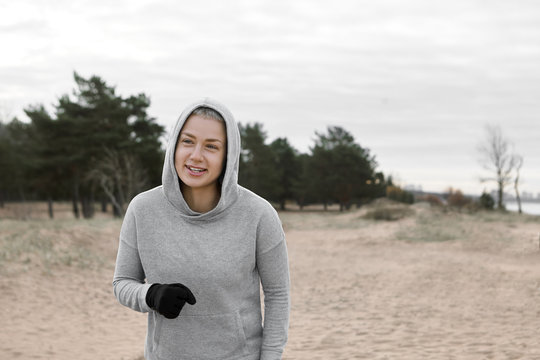 People, active lifestyle, vitality, sports and determinatio concept. Picture of beautiful slim young female athlete wearing black gloves and hoodie spending weekend outdoors, having walk or run
