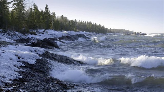 Rough winter waves breaking in afternoon sunlight on frozen winter shoreline, Lake Superior, Upper Peninsula, Michigan. 4K UHD