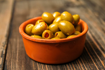 Olives filled with paprika in a retro style ceramic bowl on a old wooden table
