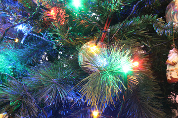 A close view of a green leaves Christmas tree with electric lights decorations, hanging ornaments and baubles in a bright colored atmosphere